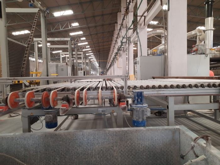 Roller conveyor carrying tiles between stages